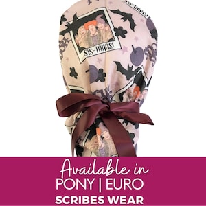 May include: A light pink scrub cap featuring a print of the Sanderson sisters from Hocus Pocus, bats, stars, and pumpkins. The cap is tied with a burgundy ribbon. The text "SIS-TAAAS!" is visible on the cap.