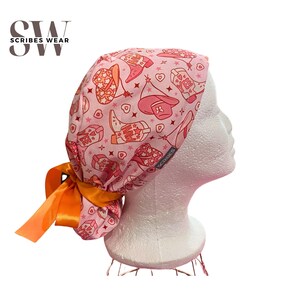 May include: Pink surgical scrub hat with a tie-back design. The hat features a pattern of pink cowboy boots, hats, and stars. The tie-back is orange satin.