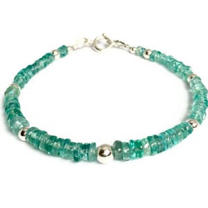 May include: A delicate bracelet made with light green gemstone beads and silver accents. The bracelet is made with a clasp closure.