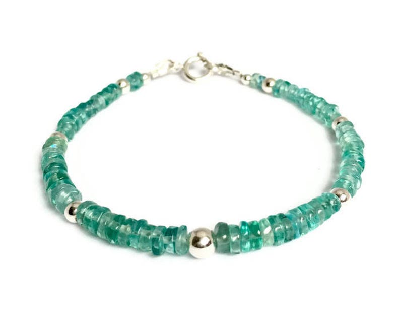 May include: A delicate bracelet made with light green gemstone beads and silver accents. The bracelet is made with a clasp closure.