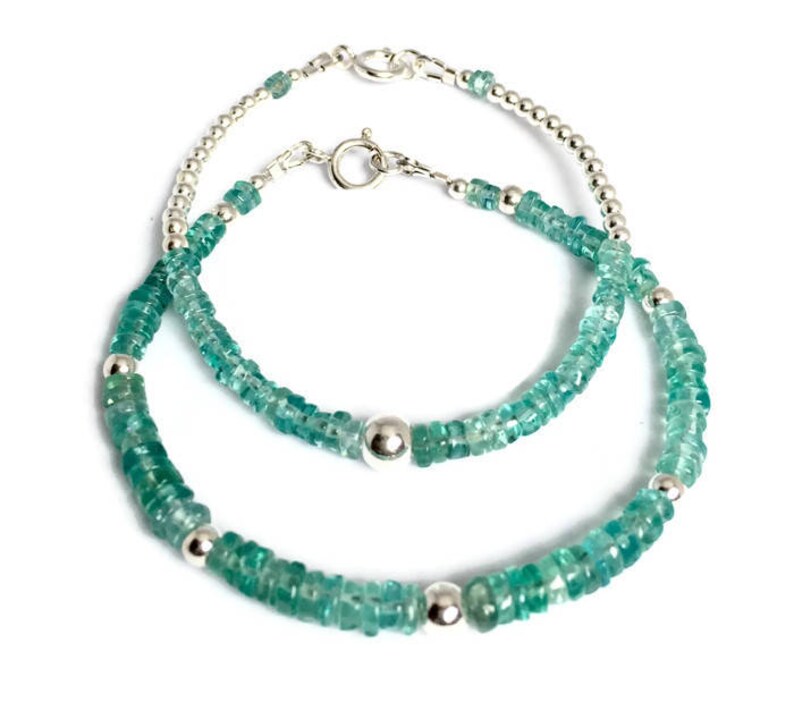 May include: Two silver bracelets with green gemstone beads. The larger bracelet has a silver bead at the clasp. The smaller bracelet has a silver bead at the clasp and a silver bead in the center.