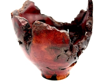 May include: A handcrafted wooden bowl with a natural, organic shape. The bowl is a rich, reddish-brown color with a rough, textured exterior. The edges are uneven, adding to its rustic charm. The bowl is likely used for decorative purposes.
