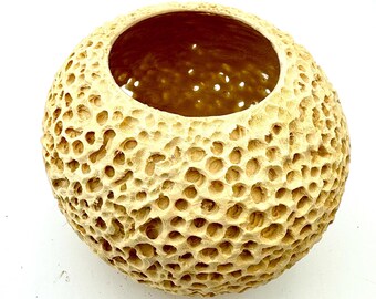 May include: A beige ceramic planter shaped like a sphere with a textured surface resembling a honeycomb pattern.