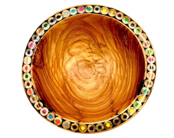 May include: A wooden bowl with a natural wood grain finish. The rim is decorated with a ring of colorful pencil tips, creating a unique and artistic design. The bowl is round and appears to be handcrafted.