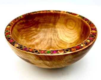May include: A handcrafted wooden bowl with a decorative rim made from colorful pencil ends. The bowl has a natural wood grain finish and a smooth, rounded shape. This unique piece is perfect for serving or as a decorative accent.