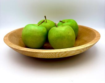 May include: Four green apples in a wooden bowl. The bowl is light brown and has a natural wood grain.