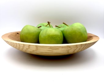 May include: A wooden bowl with a natural finish holds a group of green apples. The bowl is made of wood and has a smooth, rounded shape.
