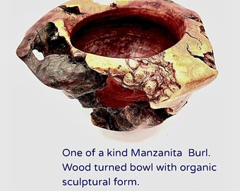 May include: A hand-turned Manzanita burl wood bowl with an organic, sculptural form. The bowl features a natural, rough exterior with a smooth, reddish-brown interior. The text on the image reads: "One of a kind Manzanita Burl. Wood turned bowl with organic sculptural form."