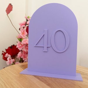 Pode incluir: Número de mesa roxo com topo arqueado e um número "40" branco na frente.