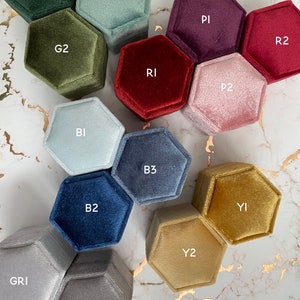 May include: A color chart of hexagonal velvet ring boxes in various colors, including green, blue, red, purple, and gold. The boxes are labeled with color codes such as G1, G2, B2, and Y2. The text "BOX COLOUR CHART" is displayed at the top.