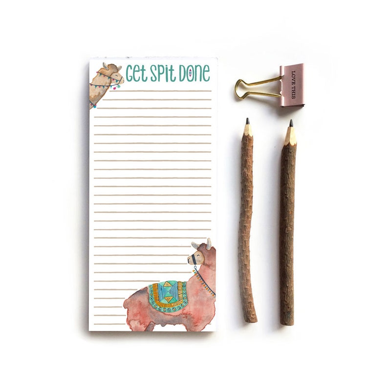 Puede incluir: Un bloc de notas con el texto "Get Spit Done" y una ilustraci&oacute;n de llama. Incluye dos l&aacute;pices de ramita y un clip rosa y dorado con "Love This". El bloc de notas tiene p&aacute;ginas rayadas.