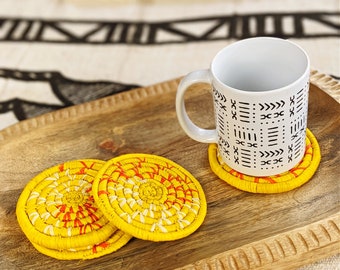 May include: Three yellow woven coasters with red accents and a white mug with a black geometric pattern on a wooden tray.
