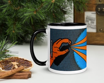 May include: A white ceramic mug with a black rim and handle. The mug features a graphic of a hand with orange fingers pointing towards a blue and orange burst of light. The background is a black and blue pattern. The text "REFLEXION IN DESIGN" is visible on the mug.