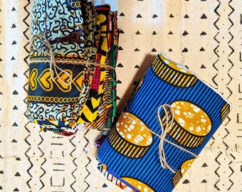 May include: A stack of colorful fabric scraps with geometric patterns, tied together with twine. The fabric is a mix of yellow, blue, black, and white.