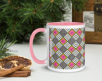May include: White ceramic mug with a pink interior and handle. The mug features a repeating geometric pattern of black and white lines, pink squares, and yellow accents. The text "REFLECTION DESIGN" is printed vertically on the side.