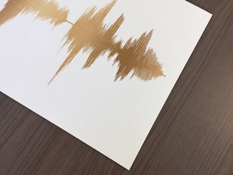 May include: A white card with a gold foil sound wave design. The sound wave is a visual representation of an audio recording.