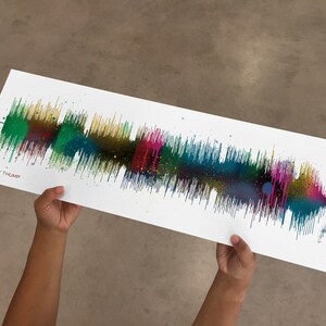 May include: A colorful sound wave print with a white background. The sound wave is made up of different colors, including green, blue, yellow, and pink. The print is signed "Ecky Thump" in the bottom left corner.