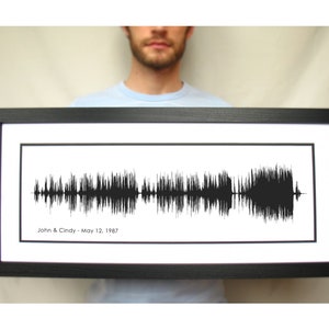 May include: A black framed print of a sound wave with the text "John & Cindy - May 12, 1987" below the wave.