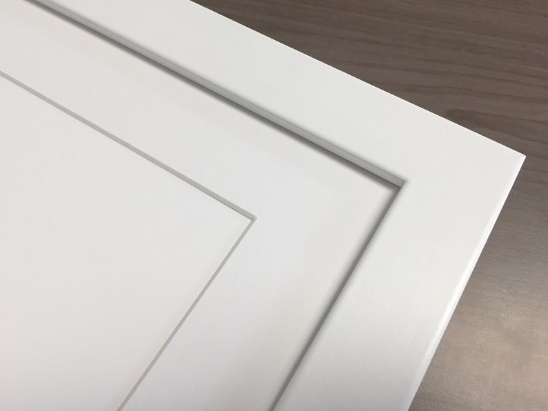 Puede incluir: Primer plano de una puerta de armario blanca con un dise&ntilde;o de panel elevado. La puerta tiene un aspecto simple y limpio y est&aacute; hecha de un material liso y plano.