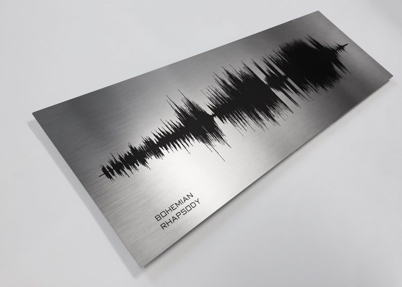 Op de afbeelding: Een zilveren metalen print met een zwarte geluidsgolfgrafiek die het nummer "Bohemian Rhapsody" voorstelt.