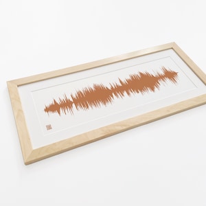 May include: A framed print of a sound wave in a light brown color. The frame is made of natural wood and has a white mat.