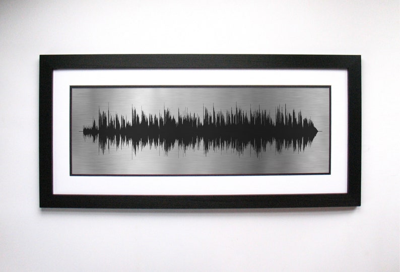 Op de afbeelding: Een metalen print van een geluidsgolf, een visuele weergave van een audio-opname, ingelijst in zwart.