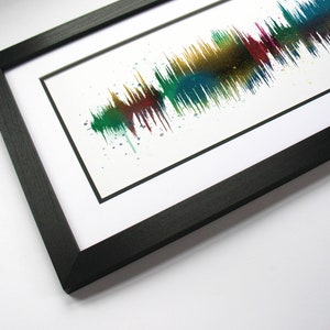 May include: A framed print of a colorful sound wave, created from a recording of someone's voice. The print is in a black frame with a white mat.