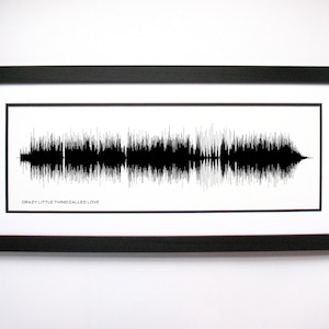 May include: A black and white framed print of a sound wave with the text "Crazy Little Thing Called Love" underneath.