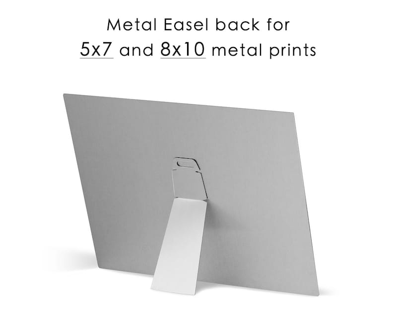 May include: Back of a metal print with a built-in easel stand. The stand is made of white metal and folds out to prop the print up. The print is designed to fit 5x7 and 8x10 metal prints.
