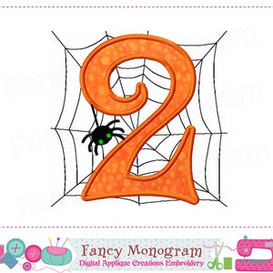 K&ouml;nnte beinhalten: Orangefarbene Zahl Zwei mit einer Spinne auf einem schwarzen Spinnennetz. Die Zahl ist im Halloween-Stil.