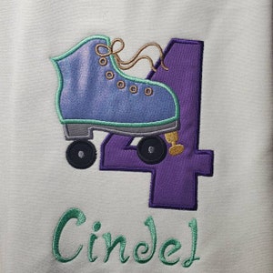 May include: Purple number four with a green and blue roller skate design. The name Cindel is embroidered in green below the number.