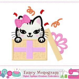 Può includere: Design ricamato con un gatto dei cartoni animati con un fiocco rosa, che esce da una scatola regalo. La scatola è beige con un motivo a croce rosa. Coriandoli arancioni e accenti rossi circondano il gatto. Il testo "Fancy Monogram" è in basso.