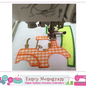 K&ouml;nnte beinhalten: Nahaufnahme einer N&auml;hmaschine, die eine Traktor-Applikation stickt. Der Traktor ist orange und wei&szlig; mit einem gr&uuml;nen Feld dahinter. Der Traktor hat einen goldenen Umriss und ein kariertes Muster.