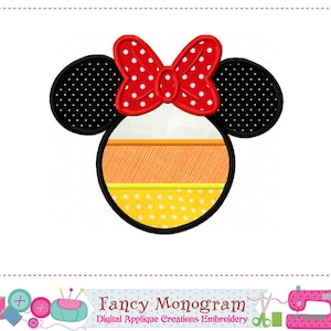 May include: A cartoon-style design featuring a Minnie Mouse head with black polka-dot ears and a red bow with white polka dots. The head is a candy corn design with orange, white, and yellow sections. The text "Fancy Monogram" is at the bottom.