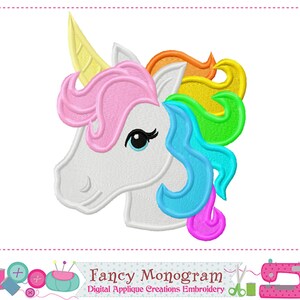May include: Embroidered unicorn head with a yellow horn, pink, orange, yellow, green, blue, and purple mane. The unicorn has a white face and a black eye. The text "Fancy Monogram" is below the unicorn.