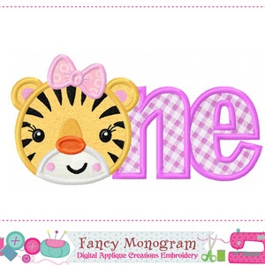 Könnte beinhalten: Stickdatei mit einem niedlichen Tiger mit einer rosa Schleife und dem Wort "one" in rosa mit einem karierten Muster. Das Design ist perfekt für eine erste Geburtstagsfeier.