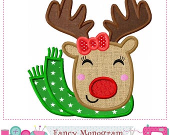 May include: An embroidery design featuring a tan reindeer head with brown antlers, a red nose, pink cheeks, and a red bow with white polka dots. The reindeer wears a green scarf with white stars. Text at the bottom reads Fancy Monogram.
