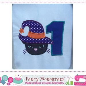 Puede incluir: Dise&ntilde;o bordado con un gato negro que lleva un sombrero de bruja de lunares morados con una banda naranja y una estrella. Un n&uacute;mero 1 azul est&aacute; al lado del gato. El texto "Fancy Monogram" est&aacute; en la parte inferior.