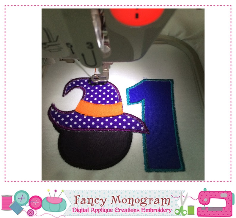 Puede incluir: Una m&aacute;quina de bordar cosiendo un dise&ntilde;o de Halloween. El dise&ntilde;o incluye un sombrero de bruja con lunares morados, una banda naranja y un caldero negro, junto con el n&uacute;mero 1 en azul. El texto "Fancy Monogram" es visible.