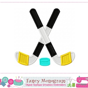 May include: Two crossed hockey sticks with a black and white design and yellow blades. A turquoise puck is between the sticks.