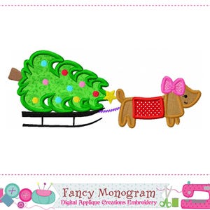 Può includere: Design ricamato con un bassotto che tira un albero di Natale su una slitta. Il cane è marrone con un fiocco rosa e una coperta rossa. L'albero è verde con ornamenti colorati e una stella d'oro. Il testo "Fancy Monogram" è in basso.
