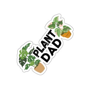 Op de afbeelding: Een sticker met de tekst "Plant Dad" in zwarte letters. De sticker toont twee potplanten, een met groene bladeren en de andere met roze en groene bladeren.