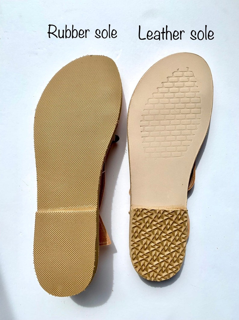 May include: Close-up of the soles of two sandals. The left sandal has a rubber sole with a textured pattern. The right sandal has a leather sole with a brick-like pattern.