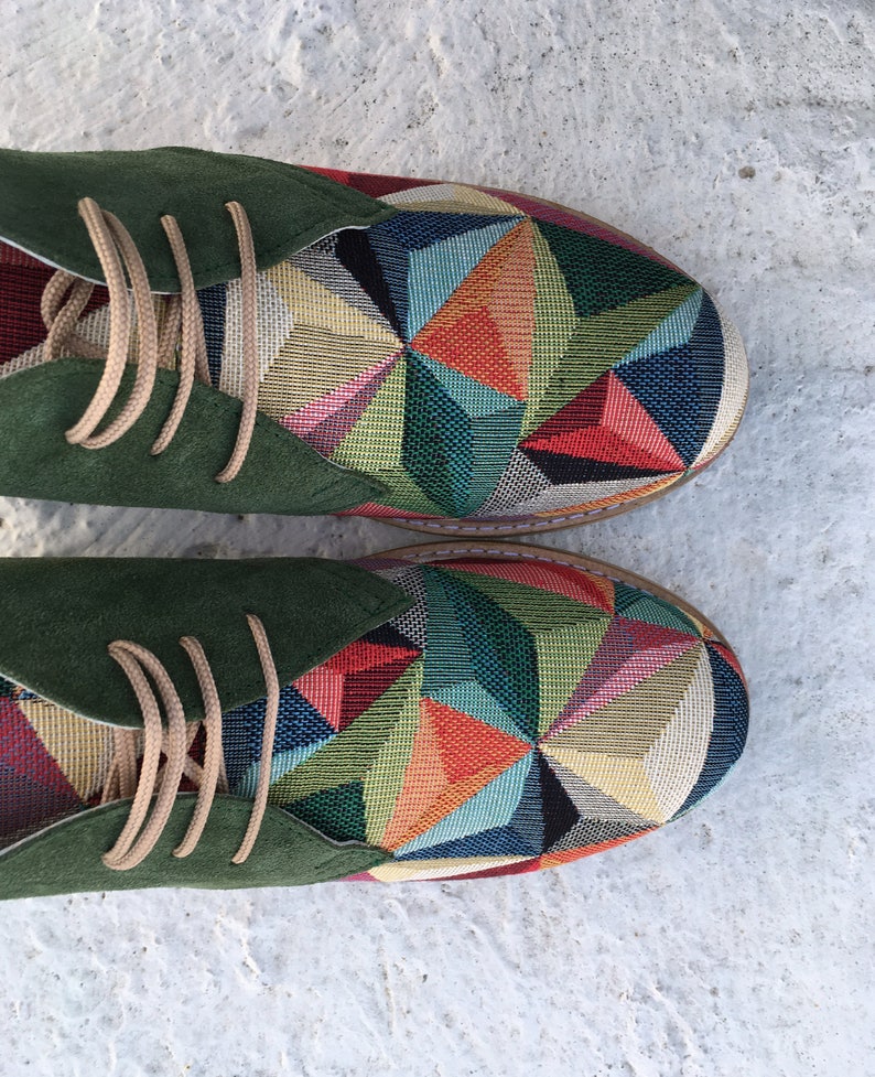 May include: A pair of green suede and fabric shoes with a geometric pattern in shades of red, blue, green, yellow, and orange.