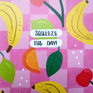 May include: Pink and white checkered background with a variety of fruit illustrations, including bananas, lemons, oranges, and cherries. The text "SQUEEZE THE DAY!" is written in black on a white background.