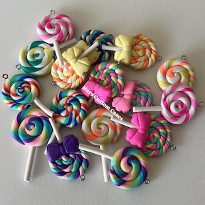 May include: A collection of colorful, handcrafted polymer clay lollipop charms. Each lollipop features a swirled design in various colors, including pink, yellow, blue, and orange, with a white stick. The text "Mars Custom Cases" is visible.