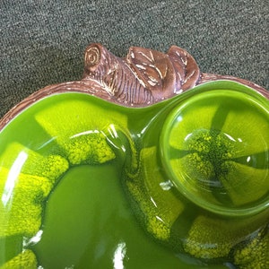 Puede incluir: Un plato de servir de cer&aacute;mica verde con un dise&ntilde;o de tortuga marr&oacute;n. El plato tiene un cuenco grande y poco profundo y un cuenco peque&ntilde;o y redondo.