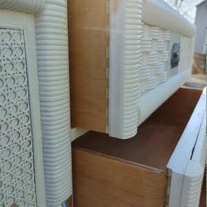 May include: White wicker dresser with two drawers. The drawers are open and reveal a light wood interior.