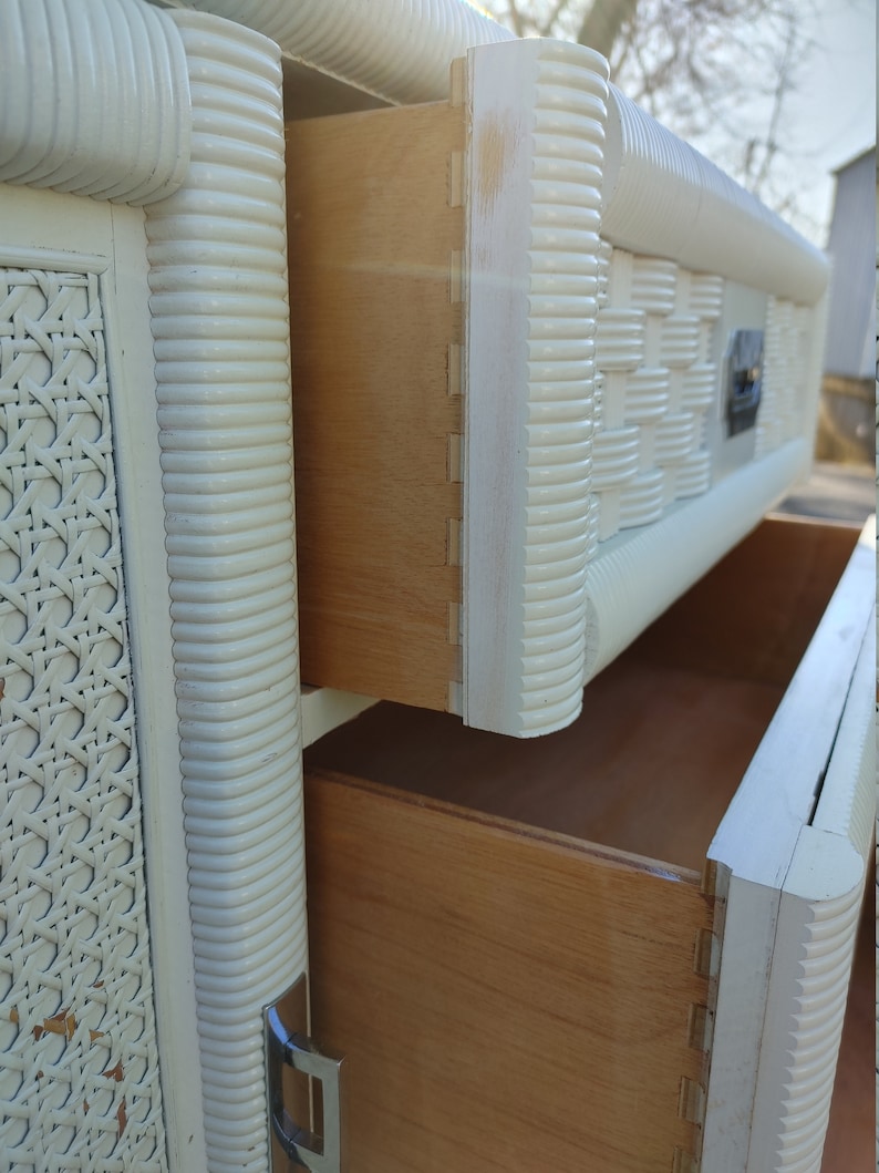 May include: White wicker dresser with two drawers. The drawers are open and reveal a light wood interior.
