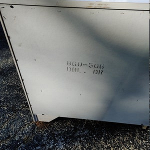 May include: A white metal cabinet with a gray back panel. The back panel has the text "860-506 DBL - DR" printed on it.